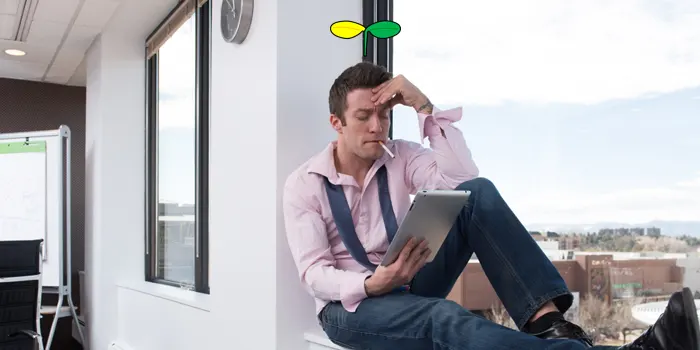 窓辺で座ってタバコを吸いながら仕事をする男性