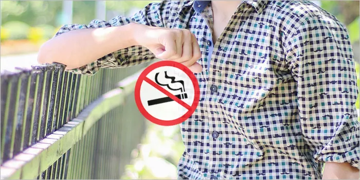 禁煙マークを持つ男性の手