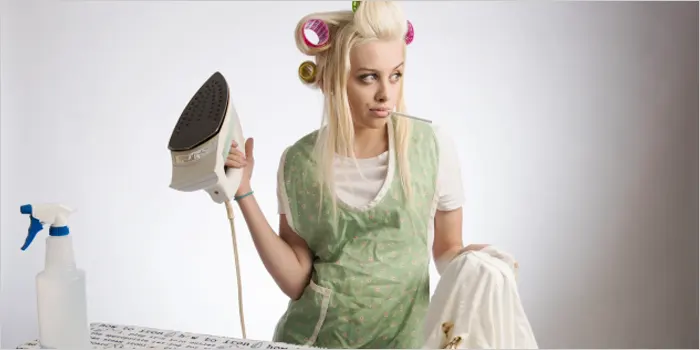 タバコを吸いながらアイロンをかける女性