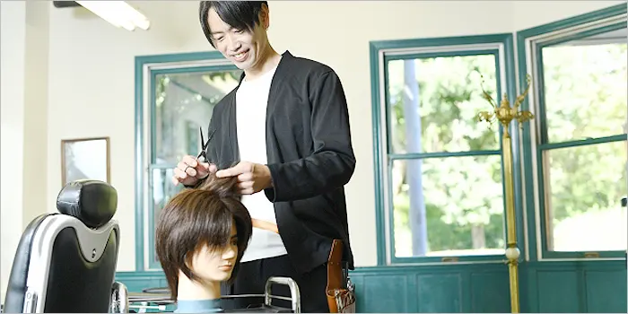 ウィッグでヘアカットの練習をする美容師