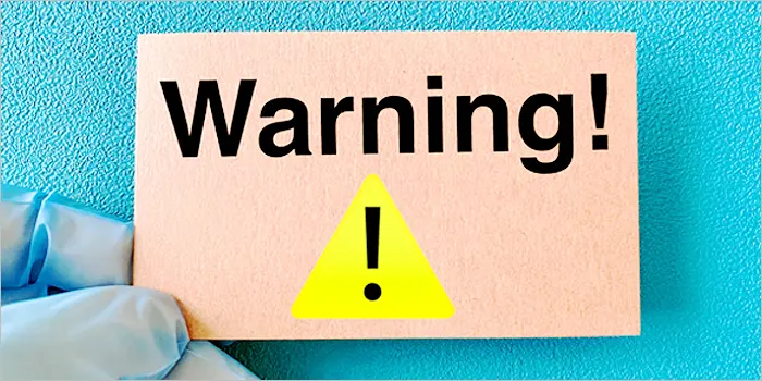 注意と書かれた紙を持つ手